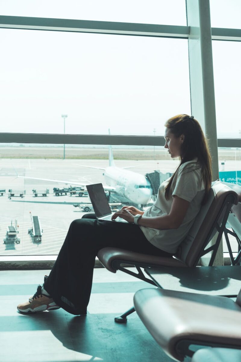 woman sitting near window while using a laptop
